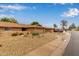Street view of a tan house with a desert rock yard and covered porch and a 2 car garage at 18211 N Conestoga Dr, Sun City, AZ 85373