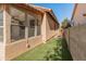 A cozy backyard featuring artificial turf, a stucco wall, and a view of the home's exterior at 19412 N 77Th Ave, Glendale, AZ 85308