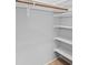 Bright walk-in closet with white shelving, white walls, and a wooden clothes rod at 19412 N 77Th Ave, Glendale, AZ 85308