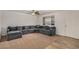 Spacious living room with a cozy gray sectional couch, ceiling fan, and natural light at 299 N Comanche Dr, Chandler, AZ 85224