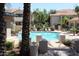 Community pool with bright blue water and surrounding palm trees and condos on a sunny day at 3830 E Lakewood Pkwy # 2162, Phoenix, AZ 85048