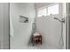 Bright bathroom with modern shower, wood bench, neutral tile, niche and window with plants at 4010 N 156Th Ln, Goodyear, AZ 85395