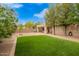 Backyard featuring artificial grass with a gravel border, a block wall, and mature trees at 4433 W Phalen Dr, Phoenix, AZ 85087
