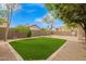 Backyard featuring artificial grass with a gravel border, a block wall, and mature trees at 4433 W Phalen Dr, Phoenix, AZ 85087