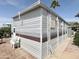 Exterior view of the mobile home, featuring a white door, brown trim and a lush, landscaped yard at 457 S Jaspar Dr, Apache Junction, AZ 85119