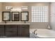 Bathroom featuring a soaking tub, double vanity, glass block window, and walk-in shower at 4932 S Verbena Ave, Gilbert, AZ 85298