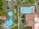 Birds-eye view of community pools with palm trees, blue lounge chairs, and buildings with tiled roofs, evoking a resort atmosphere at 77 E Atole Ct, Queen Creek, AZ 85140