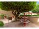 Charming courtyard featuring a stone fountain, chairs, and a mature tree for shade at 9442 N 106Th Pl, Scottsdale, AZ 85258