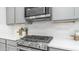 Modern kitchen featuring stainless steel appliances, gray cabinetry, a white backsplash, and a gas range at 13511 W Cassia Trl, Peoria, AZ 85383