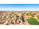 Shows an aerial perspective of a vibrant neighborhood with green spaces and neatly arranged homes under a clear sky at 17704 W Tasha Dr, Surprise, AZ 85388