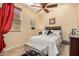 Cozy bedroom with a ceiling fan, wood floors, and a window with red curtains at 17704 W Tasha Dr, Surprise, AZ 85388