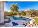 Inviting backyard pool features a rock waterfall, mature trees, and a cozy lounge area at 17704 W Tasha Dr, Surprise, AZ 85388