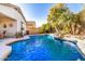 Inviting backyard pool with rock waterfall, lush palm trees, and desert landscaping at 17704 W Tasha Dr, Surprise, AZ 85388
