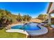 Resort-style pool with rock waterfall feature, mature landscaping, and backyard seating at 17704 W Tasha Dr, Surprise, AZ 85388