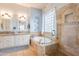 Elegant bathroom featuring double sinks, a soaking tub, and a glass-enclosed shower at 1919 S Granite St, Gilbert, AZ 85295