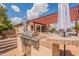 Outdoor kitchen with stainless steel grill, red pergola, covered patio, and comfortable seating area at 1919 S Granite St, Gilbert, AZ 85295