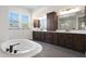 Bright bathroom with soaking tub, large windows, dark cabinets, and tile flooring at 20775 W Rattler Rd, Buckeye, AZ 85396