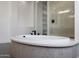 Close up of white soaking tub with black faucet and textured gray base at 20775 W Rattler Rd, Buckeye, AZ 85396