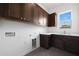 Laundry room with dark wood cabinets, white countertop and utility sink at 20775 W Rattler Rd, Buckeye, AZ 85396