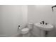 Stylish powder room features modern fixtures, toilet, and pedestal sink at 20775 W Rattler Rd, Buckeye, AZ 85396