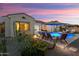 Backyard with a pool, lounge chairs, desert landscaping, and soft lighting at dusk at 20977 W Mariposa St, Buckeye, AZ 85396