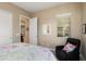 Well-lit bedroom features a chair, window with blinds, and view into an adjacent room at 20977 W Mariposa St, Buckeye, AZ 85396