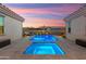 Pool and hot tub with underwater lights, lounge chairs, umbrellas, and desert landscaping at sunset at 20977 W Mariposa St, Buckeye, AZ 85396