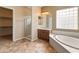 Spacious bathroom featuring a glass-enclosed shower, a large soaking tub, and neutral tile flooring at 26473 W Runion Ln, Buckeye, AZ 85396