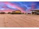 Expansive equestrian property featuring a barn and riding area under a beautiful sunset sky at 29756 N Varnum Rd, San Tan Valley, AZ 85143