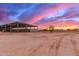 Equestrian facility with covered stalls and ample space, set against a picturesque sunset backdrop at 29756 N Varnum Rd, San Tan Valley, AZ 85143