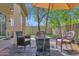 Cozy back patio with a gas fire pit, umbrella, and three cushioned chairs overlooking the manicured yard at 30430 N 42Nd Pl, Cave Creek, AZ 85331
