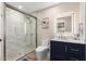 Bathroom featuring a shower with marble tile, blue vanity with light countertop, and lighted mirror at 3209 E Marilyn Rd, Phoenix, AZ 85032