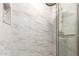 Shower featuring marble tile, a rainfall shower head, and a glass door with a silver handle at 3209 E Marilyn Rd, Phoenix, AZ 85032
