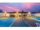 A well-maintained tennis court at dusk, complemented by a covered patio and exterior lighting at 3209 E Marilyn Rd, Phoenix, AZ 85032