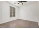 A bright, empty bedroom with tile flooring, a modern ceiling fan, and a large window at 3591 S Ranger Trl, Gilbert, AZ 85297