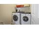 Convenient laundry room features a washer, dryer, storage space, and a shelf for organizing supplies at 41369 W Parkhill Dr, Maricopa, AZ 85138