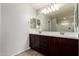 Bright bathroom featuring a dual sink vanity with dark wood cabinets and a large mirror reflecting the walk-in shower at 4253 E Palo Verde St, Gilbert, AZ 85296