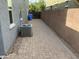 A paver side yard with AC unit, block wall, a blue garbage can and minimal landscaping at 4253 E Palo Verde St, Gilbert, AZ 85296