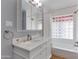 Bright bathroom featuring a white vanity with marble countertop and a glass block window above the tub at 4440 E Campbell Ave, Phoenix, AZ 85018