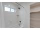 White tiled bathroom with shower head, bathtub and open closet space for storage at 4440 E Campbell Ave, Phoenix, AZ 85018