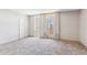 Neutral carpeted bedroom with a door to the exterior and windows with adjustable blinds at 6928 E 3Rd St, Scottsdale, AZ 85251