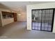 Open living room with sliding glass doors, a pass-through to the kitchen, and neutral carpet at 6945 E Cochise Rd # 108, Paradise Valley, AZ 85253