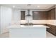 Stylish kitchen with a large island, white tile backsplash, and sleek stainless steel range hood at 7433 W Buckhorn Trl, Peoria, AZ 85383