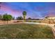Large, landscaped backyard featuring a sparkling pool, mature trees, and cozy seating area with sunset sky at 863 W Kiva Ave, Mesa, AZ 85210
