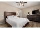 Inviting bedroom with a wooden bed frame, dresser, side table with lamp, and a ceiling fan at 8637 E Weldon Ave, Scottsdale, AZ 85251