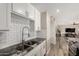 Bright kitchen showcasing granite counters, stainless faucet, white cabinets, and modern subway tile backsplash at 8637 E Weldon Ave, Scottsdale, AZ 85251