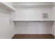 Spacious, all-white walk-in closet with shelves, metal racks, and hardwood-style floors provides ample storage at 1150 E Tyson St, Chandler, AZ 85225