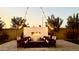 Outdoor entertaining space with an open fireplace as the focal point, surrounded by lounge chairs and ambient lighting at 11818 W Luxton Ln, Avondale, AZ 85323