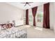 Bright bedroom with carpet, burgundy curtains, ceiling fan and a white dresser at 11818 W Luxton Ln, Avondale, AZ 85323