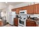 Bright kitchen with white appliances, wood cabinets, and a built-in microwave, ideal for cooking and dining at 12371 W Hadley St, Avondale, AZ 85323